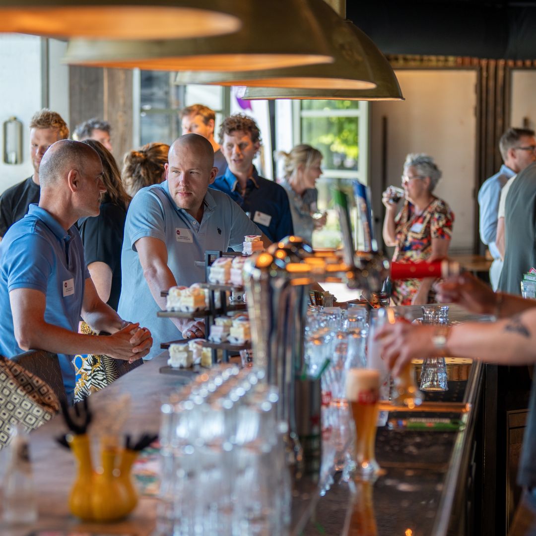 Gezellige sfeer tijdens bedrijfsborrel in de evenementenruimte van RNGRZ
